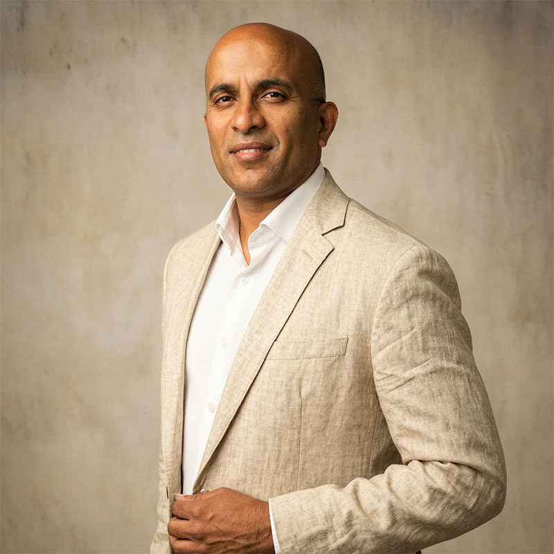 Man in a beige suit jacket and white shirt standing against a neutral background, looking at the camera, embodying the professionalism of an Interim CFO for San Francisco’s dynamic non-profit and for-profit sectors.